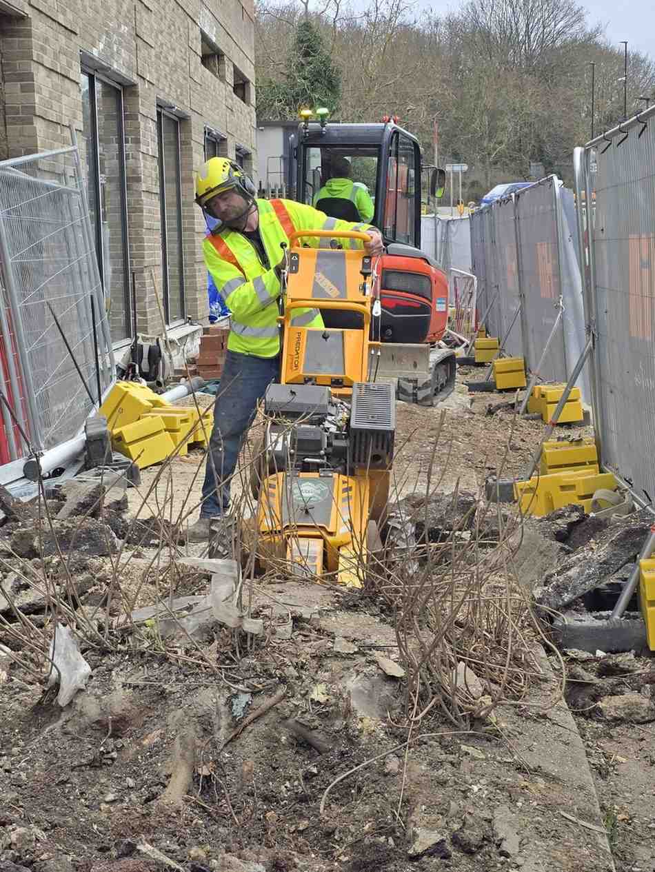 Stump grinder removing roots inside a fenced construction site
