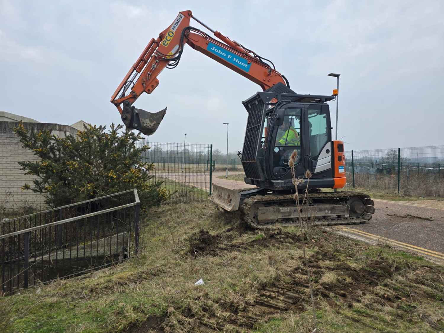 Excavator clearing a roadside embankment on an industrial estate