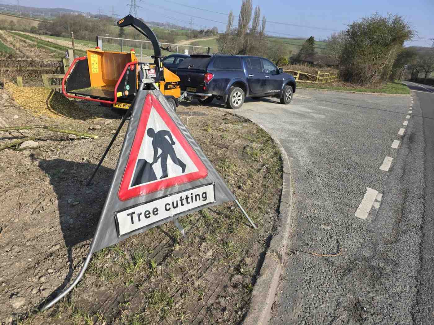 Woodchipper and tree-cutting road sign set up for roadside works